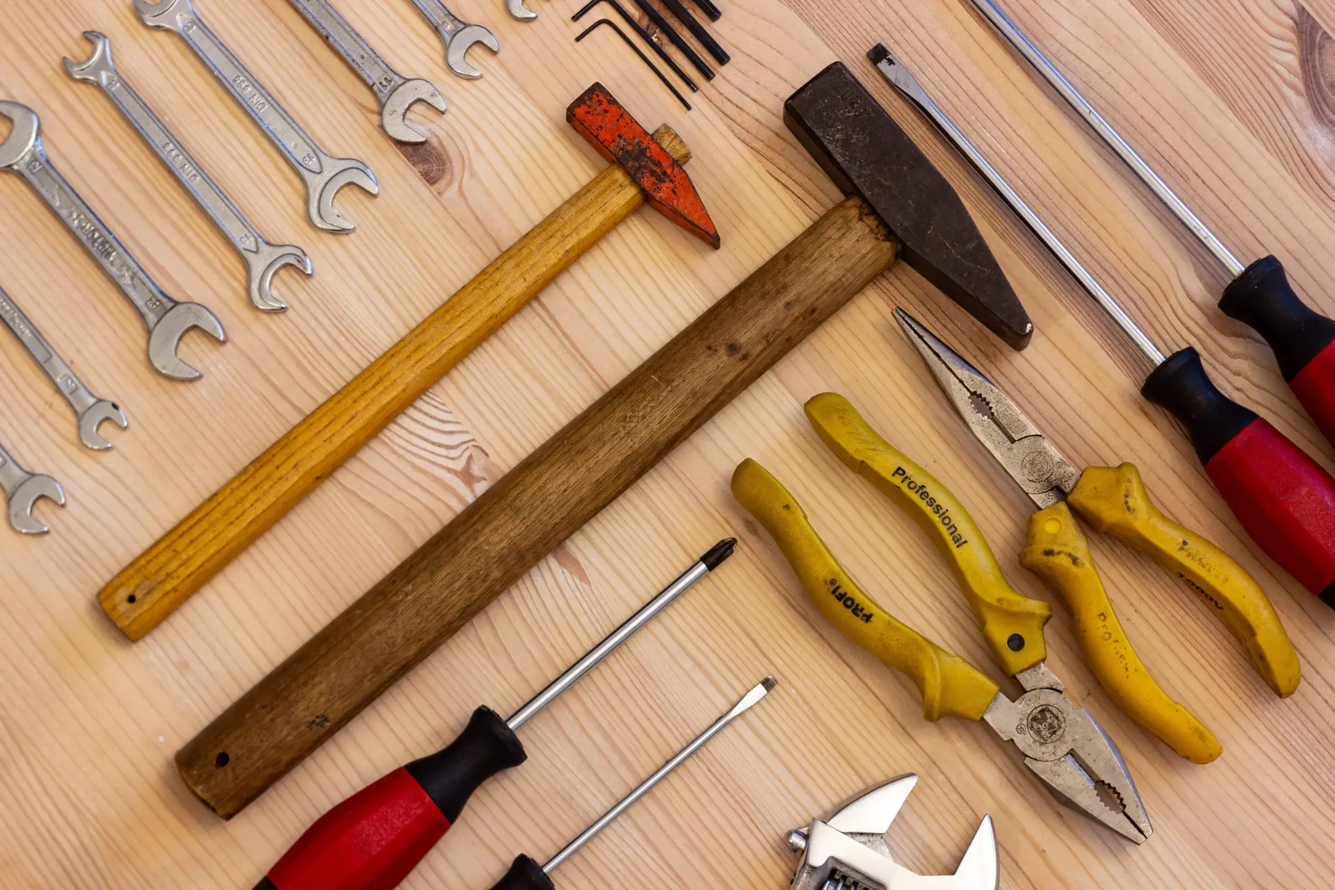 Startseite A variety of hand tools including wrenches, screwdrivers, and pliers on a wooden surface.